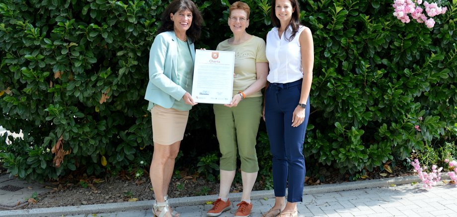 Bürgermeisterin Sabine Noll und die Pflegeguides Stefanie Schubert und Tanja Kolek mit der unterzeichneten Charta.