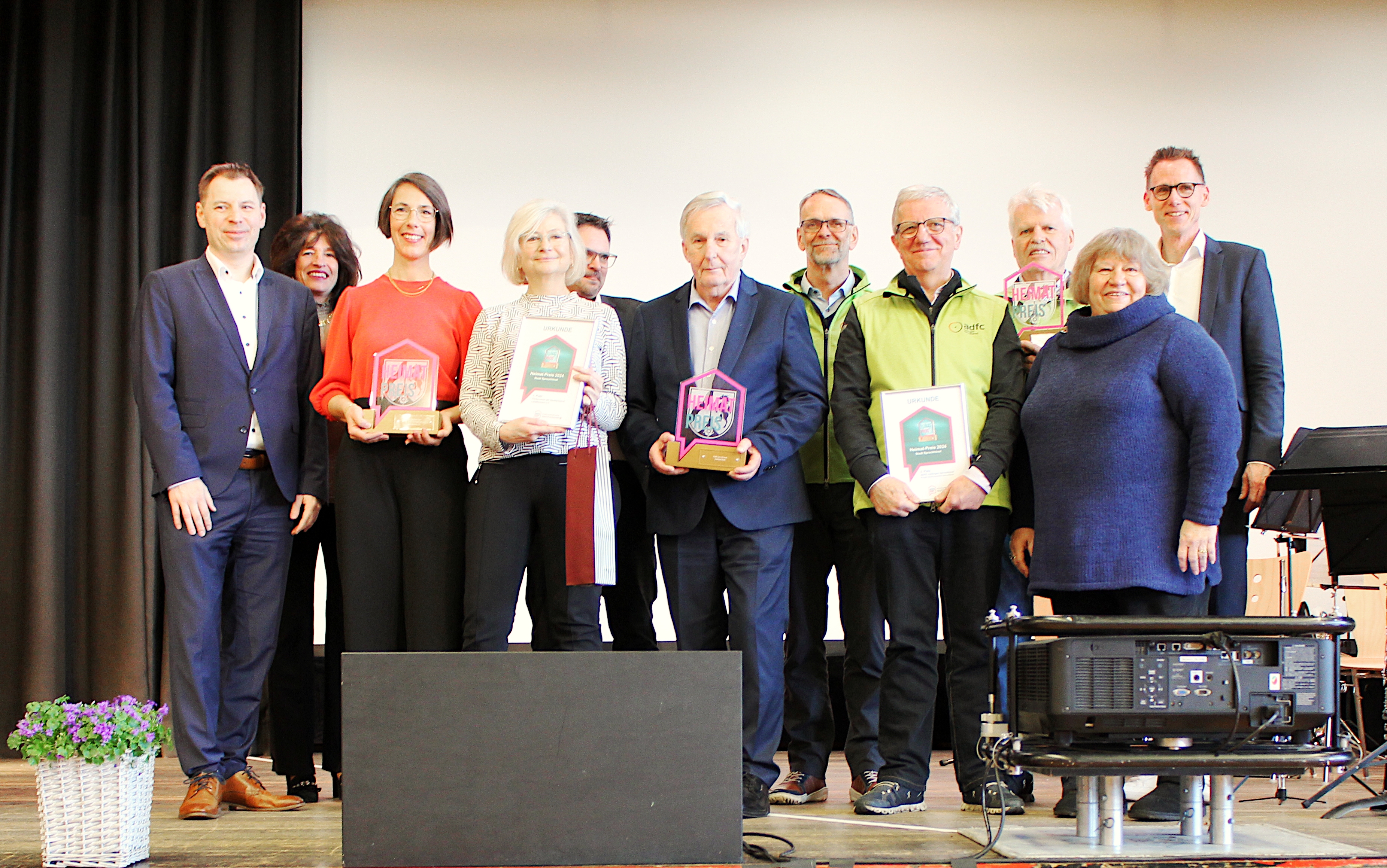 Die Preisträger des Heimatpreises 2024 (1. Platz: Förderverein Lesezeichen e.V., 2. Platz: Hartmut Kroll, 3. Platz: ADFC Hattingen-Sprockhövel) zusammen mit Bürgermeisterin Sabine Noll, den stellvertretenden Bürgermeister*innen und Gastredner Frank Busemann. Die Preisträger des Heimatpreises 2024 (1. Platz: Förderverein Lesezeichen e.V., 2. Platz: Hartmut Kroll, 3. Platz: ADFC Hattingen-Sprockhövel) zusammen mit Bürgermeisterin Sabine Noll, den stellvertretenden Bürgermeister*innen und Gastredner Frank Busemann.