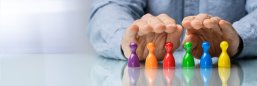 Spielfiguren_verschiedene Farben Hand schützt bunte Spielfiguren