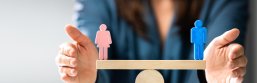 Gleichstellung Ausgeglichene Waage mit einer weiblichen und einer männlichen Holzpuppe