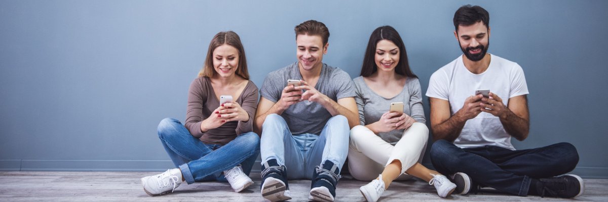 Junge Leute benutzen Smartphones und sitzen auf dem Boden