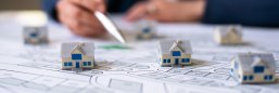 Architektenzeichnung Kleine Haus-Modelle stehen auf einem Grundriss