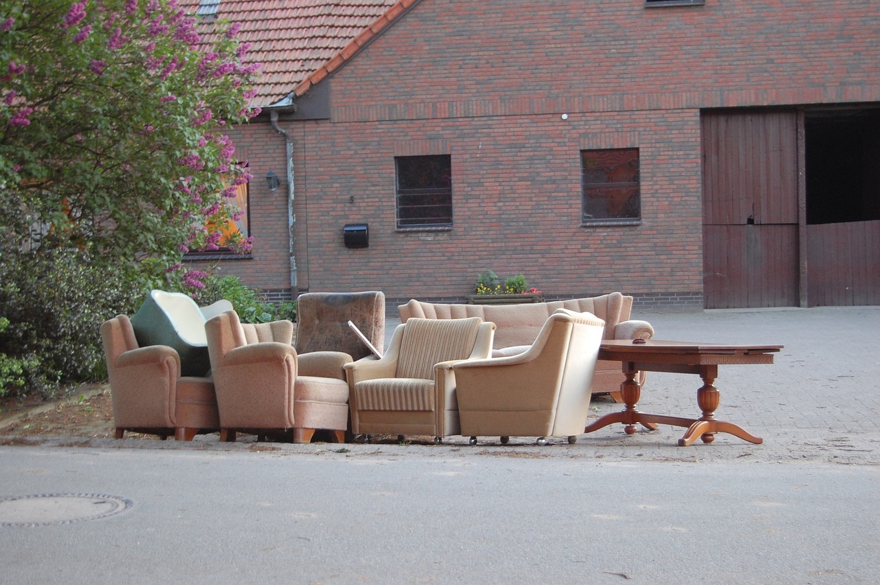 Sperrmüll Ein alter Tisch, ein Sessel und eine Couch stehen als Sperrmüll vor einem Bauernhaus