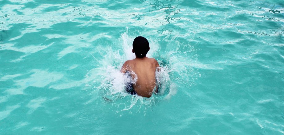 Kind mach Arschbombe Ein Kind springt ins Wasser