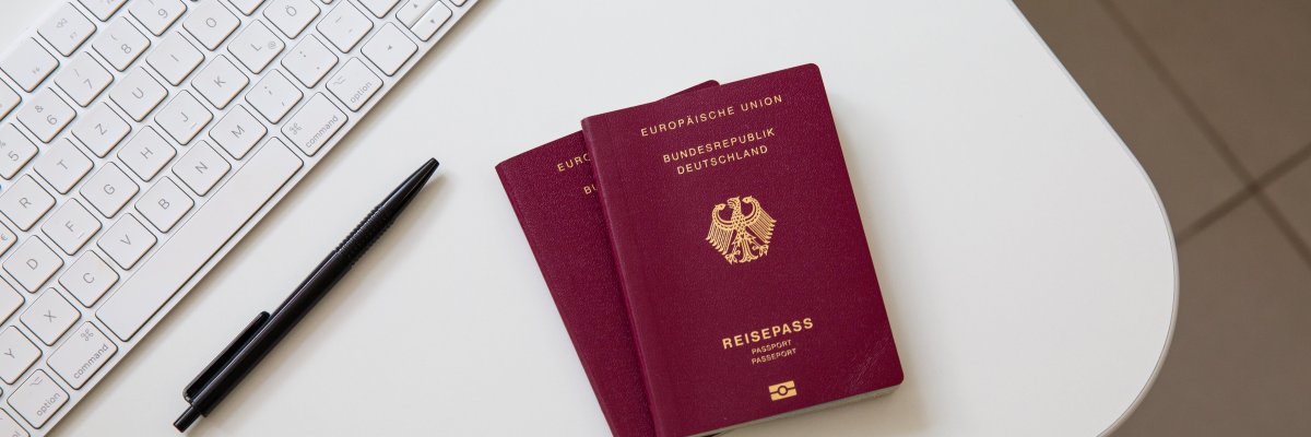 PantherMedia B714139400 Draufsicht auf einen deutschen Pass auf weißem Tisch, mit schwarzer Pfanne, Computertastatur und Maus.