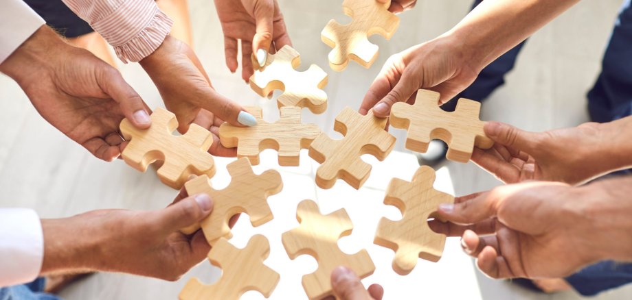 Company employees playing game and joining pieces of jigsaw puzzle during team building activity